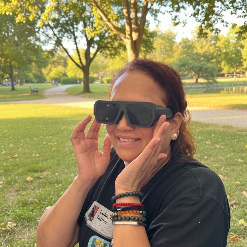 A woman in a park holding the glasses to her face