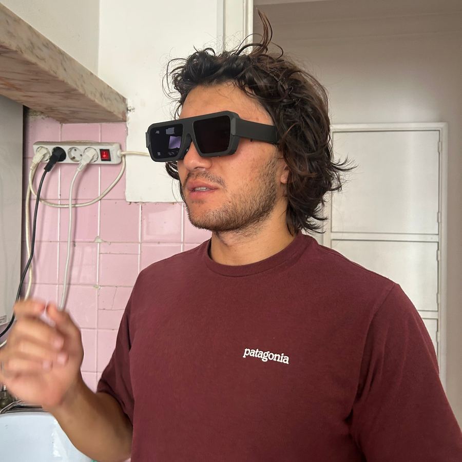 A man in a maroon T-shirt trying the glasses in a kitchen
